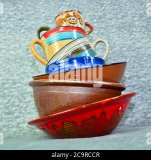 A small tower of high piled colourful crockery, bowls and cups Stock Photo
