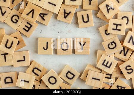 Top down view, pile of square wooden blocks with word JOY on white board. Stock Photo