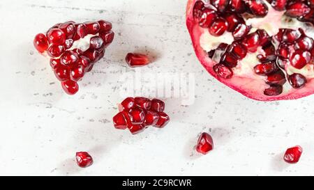 Tabletop view, pomegranate, gem like fruits scattered on white concrete board Stock Photo