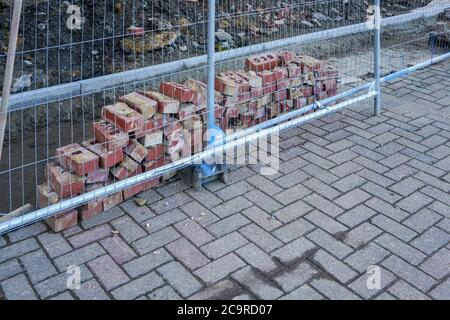 Small pile of bricks, behind steel fencing at construction site Stock Photo
