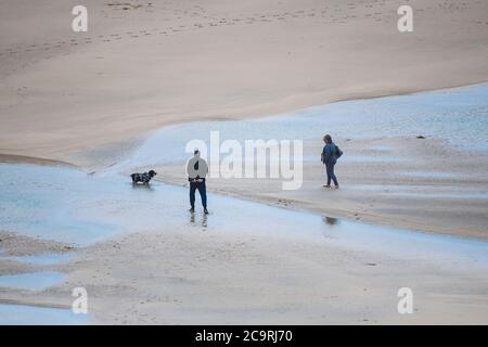 Dog walkers on Crantock Beach in Newquay in Cornwall. Stock Photo