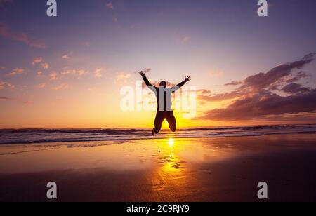 Jumping man on sunset beach Stock Photo