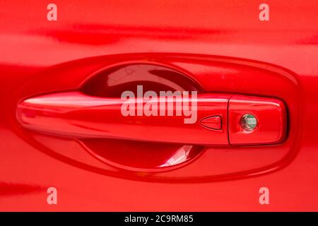 the handle of the car of red color with a keyhole and the button keyless entry. Stock Photo