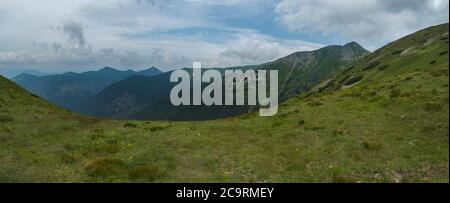 View from tatra mountain trail on Baranec to Western Tatra mountains or Rohace panorama. Grassy meadow hills, blue sky. Tatra mountain in summer Stock Photo