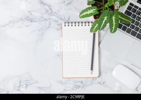 Pencil on blank notebook with laptop and mouse on marble table background, top view and copy space, Business and workplace concept Stock Photo