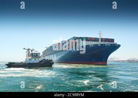 A tug assists a container ship arriving at the Port of Southampton ...