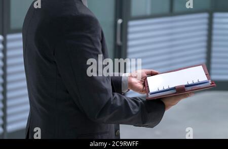Businessman holding and open up diary or planner in his hands. Meeting or appointment concept. Stock Photo