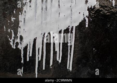 White paint dripping down on a dirty structured glass texture for background Stock Photo