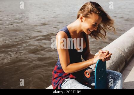 beautiful blonde woman posing with a skateboard in a city park Stock Photo