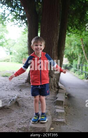 Happy and smiling four-year old boy pretending to be a statue at Ilkley in West Yorkshire. Stock Photo