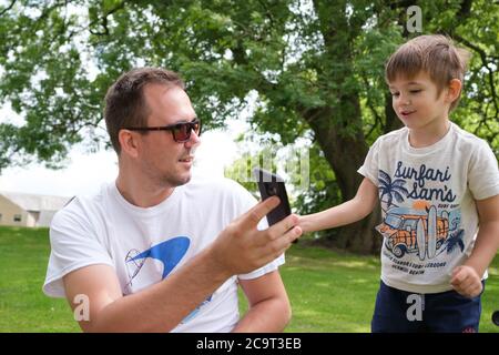 A father and son sharing a phone conversation outdoors Stock Photo