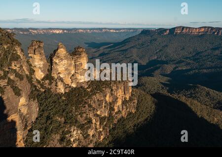 Three Sisters scenery from Echo Point, Blue Mountains National Park, Australia during sunset where golden tint of sunlight cast over majestic rock Stock Photo