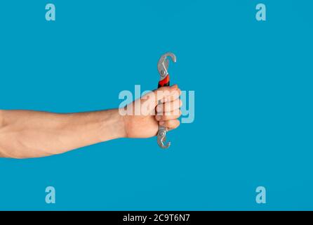 Unrecognizable man holding universal spanner over blue background, blank space Stock Photo