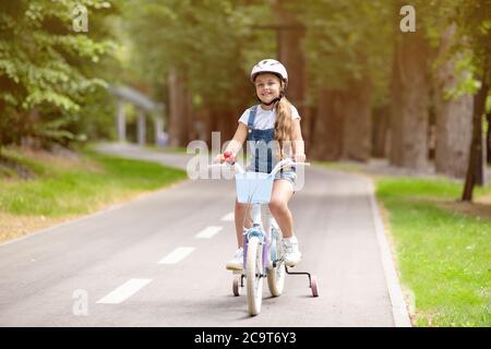 Little Girl Riding Bicycle Wearing Protective Helmet Having Fun Outdoors Stock Photo