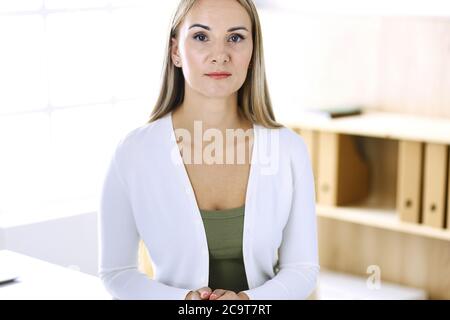 Business woman headshot while working with computer at the desk in modern office. Designer or female lawyer looks beautiful in white casual clothes Stock Photo