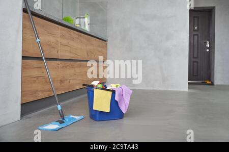 Cleaning equipment at home. Mop and plastic bucket with rags, detergents and different cleaning products on the floor in the modern kitchen. Cleaning service, Housework, Housekeeping Stock Photo