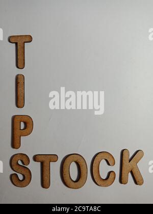 Stock tips word presented on white surface with wooden cross text cloud frame art business learning background. Stock Photo