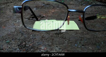 Future word displaying on paper slip behind the specs glass with black soil background business leadership concept. Stock Photo
