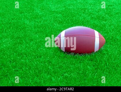 An american football on a green grass field during the day. Stock Photo