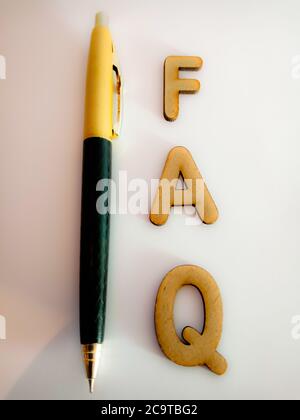 FAQ text presented for active business education concept on paper pen background. Stock Photo