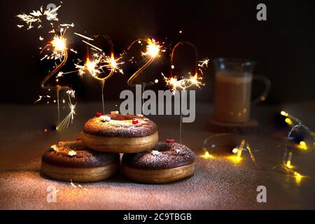 Donuts with christmas decoration with an igniting 2020 Shaped Sparkler. Stock Photo