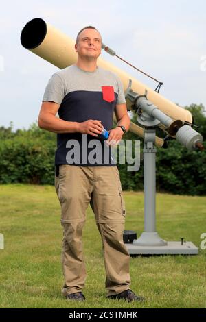 17 July 2020, Saxony-Anhalt, Parey: Thomas Becker, hobby astronomer, is standing in front of his telescope in Parey/Havelaue. As a nature park employee, Becker is in charge of the 'Sternenpark' project and brings it closer to guests, for example during nighttime starwalks. For the tourism industry in Havelland and Altmark, this offers the chance to attract new groups of visitors. Many accommodation providers have already adapted to the special clientele. Telescopes and hire telescopes are also part of the offer, as is the possibility of a late checkout after a nocturnal star trek. Photo: Peter Stock Photo