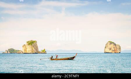 Krabi, Thailand, November 9, 2017: Thai long tail fishing boat in the Andaman Sea with islands and Krabi coastline on the horizon Stock Photo