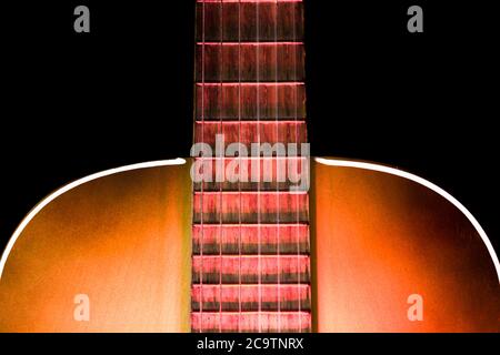 Acoustic guitar soundboard with part of the fretboard and illuminated with red light from below Stock Photo