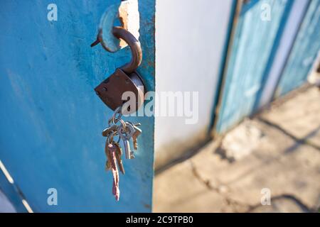 A lock with a bunch of keys hanging in an open metal door. Stock Photo