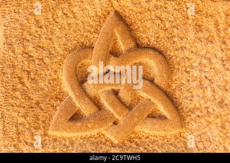 Interlaced triquetra with heart on a stone wall Stock Photo