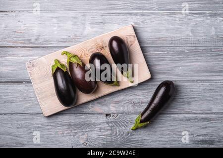 Fresh ripe eggplant on wooden cutting board, grey wood backdrop background, top view Stock Photo