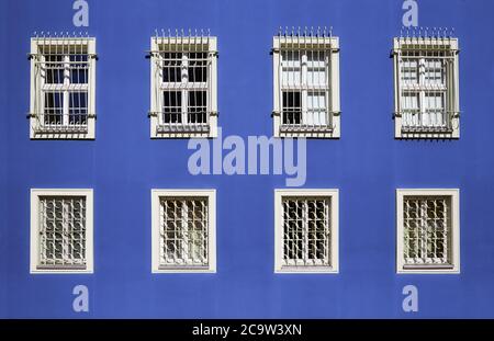 Barred windows in a blue wall. Stock Photo