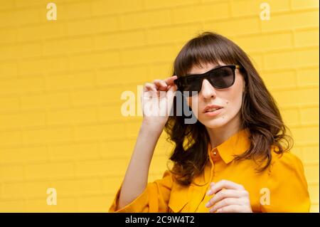 portrait of a girl in sunglasses against the yellow wall. Empty place to write text. Full length body size photo beautiful amazing she her dark skin l