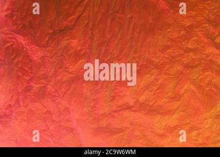 Background from purple recyclable polyethylene in neon orange light. Eco, zero waste, alternative to plastic concept. Flat lay. Horizontal. Closeup. Stock Photo