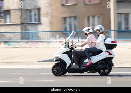 Belgrade, Serbia - July 31, 2020: Mature couple riding on a three wheels motorbike in city street, and a woman is checking time at her wrist watch