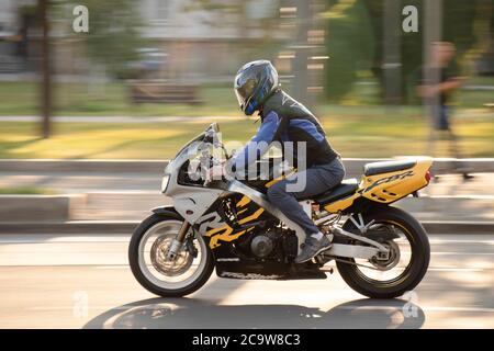 Belgrade, Serbia - July 21, 2020: Man riding a fast motorbike in empty city street by the park, in summer sunset Stock Photo