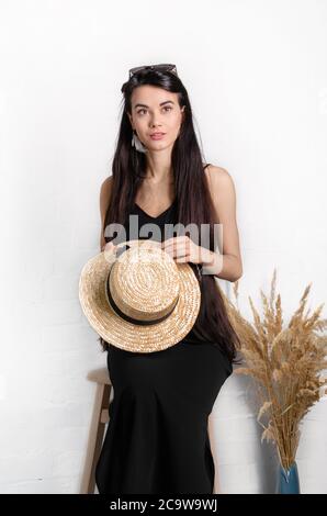 young girl with a straw hat on a white background, beautiful brunette in glasses, closeup Stock Photo