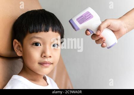 Checking measure fever levels asian little child using digital infrared thermometer in hospital. Stock Photo