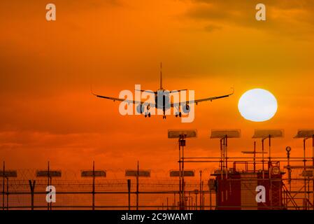 Silhouette of airplane during landing in front of amazing evening sky with sun, space for text Stock Photo