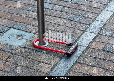 A D lock bike lock locked around a pole on the street Stock Photo