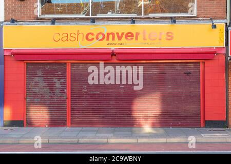 The exterior or facade of a closed Cash converters shop or store with the metal shutters down Stock Photo
