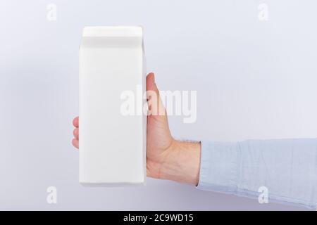 Carton of milk or juice package in hand on white background. Copy space, mock up. Stock Photo