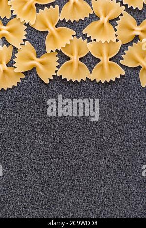 Farfalle Italian pasta. Bow Tie Pasta on grey background. Vertical frame, close up. Space for text. Stock Photo