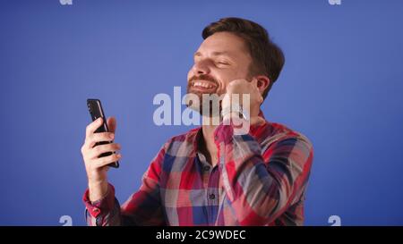 Attractive excited young bearded man having a conversation on the smartphone using the wireless headphones. High quality photo Stock Photo