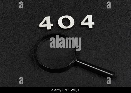 Numerals 404 and magnifying glass on black background. Error concept Stock Photo
