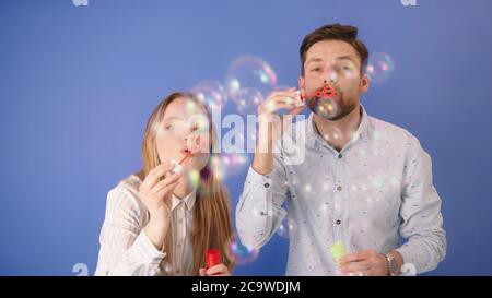Soap bubbles on CAM. Man and woman are having fun with soap bubbles. Isolated on blue. High quality photo Stock Photo
