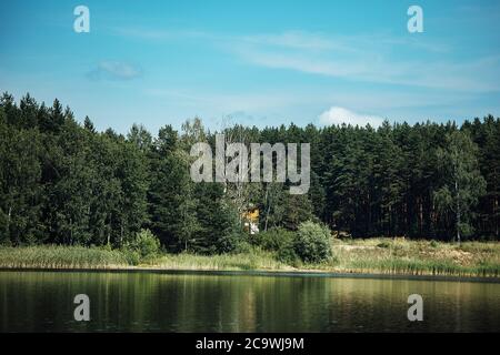 overgrown grassy shore, summer landscape with a calm river with water views of the lake and the shore from the water Stock Photo
