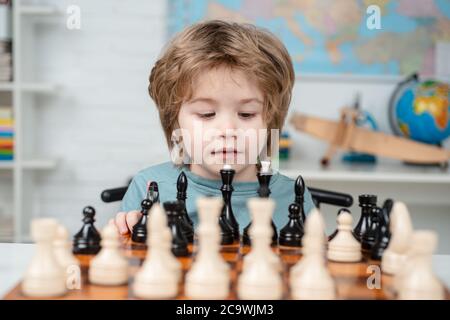 Pupil kid thinking about his next move in a game of chess. Concentrated  little boy sitting at the table and playing chess Stock Photo - Alamy