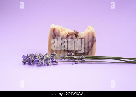 A handmande organic soap with beautiful fresh lavender near it on the purple background. Organic Spa Cosmetics. Close up. Copy Space. Stock Photo