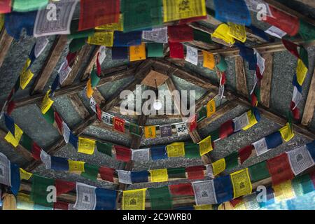 Bright colorful buddhist praying flags hanging from a ceiling in Nepal mountains Stock Photo
